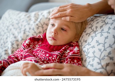 Sick child, toddler boy lying on the couch with his white puppy in living room with fever, resting at home - Powered by Shutterstock