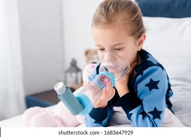 sick child using inhaler with spacer in bedroom - Powered by Shutterstock