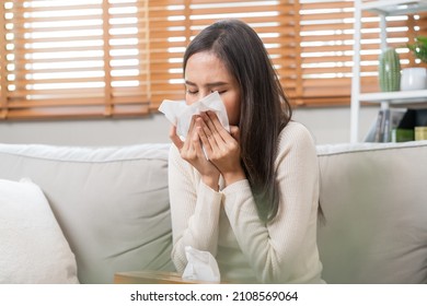 Sick, Coronavirus covid-19 asian young woman, girl headache under blanket have a fever, flu and use tissues paper sneezing nose, runny sitting on sofa bed at home. Health care on virus person.