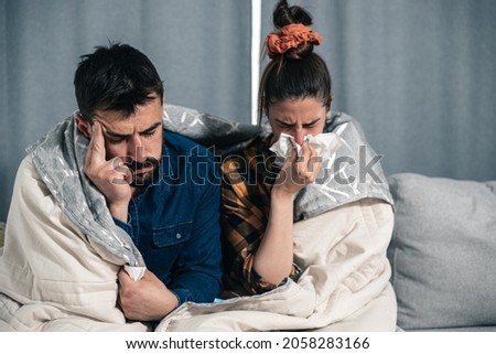 Sick couple catch cold. Man and woman sneezing, coughing. People got flu, having runny nose. Selective focus