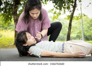 Sick Daughter Is Fainted And Fallen On Floor,asian Mother Help,take Care,child Girl With Heat Stroke,high Temperature,female Unconscious Fell To The Ground Suffer From Sunstroke Very Hot In Outdoor Park