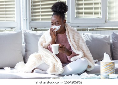 Sick day at home. African American woman has runny nose and common cold. Cough. Closeup Of Beautiful Young Woman Caught Cold Or Flu Illness. Portrait Of Unhealthy Girl Feeling Pain and running nose. - Shutterstock ID 1564205962
