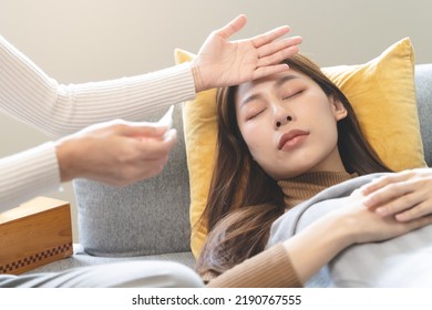 Sick Day At Home In Winter Season. Young Asian Woman Lying On The Bed Have A Fever And Her Husband Checking Thermometer And Measure Body Temperature.