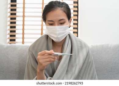 Sick Day At Home In Winter Season. Young Asian Woman Have A Fever Checking Thermometer And Measure Body Temperature.