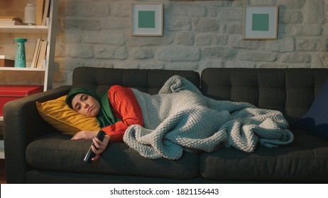 A Sick Day At Home. The Young Woman Wearing A Turban Is Warming Up With A Blanket, Watching TV.