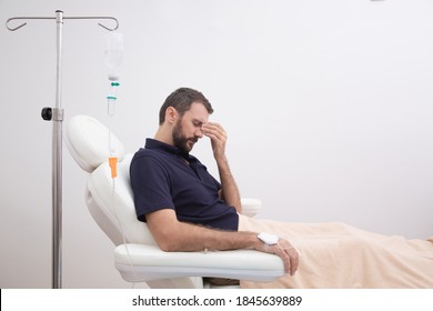 Sick, dehydrated or hangover patient man receiving vitamin IV infusion drip in hospital or beauty salon. Healthcare and medicine concept