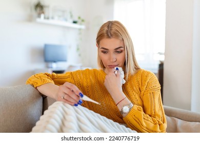 Sick desperate woman has coronavirus. Covid 19 , cold, sickness, allergy concept. Pretty sick woman has runnning nose, rubs nose with handkerchief and looking at temperature on thermometer - Shutterstock ID 2240776719