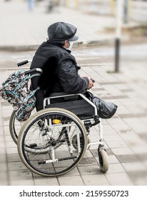 A Sick Disabled Person In A Wheelchair Asks For Alms On A City Street