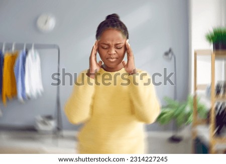 Sick, dizzy, young woman suffering from vertigo, headache. Portrait of attractive stressed African American woman touching her head suffering from dizziness, migraine, overwork