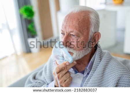 Sick elderly man making inhalation, medicine is the best medicine. Ill senior man wearing an oxygen mask and undergoing treatment for covid-19. Senior man with an inhaler