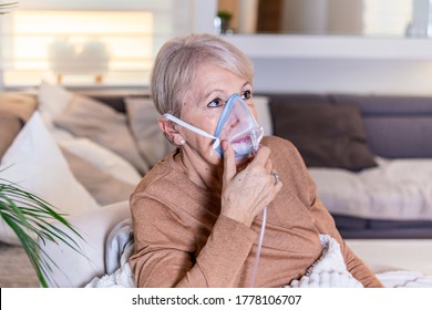 Sick Elderly Woman On Oxygen Mask Inhalation, Pneumonia Coronavirus Pandemic. Ill Senior Woman Wearing An Oxygen Mask And Undergoing Treatment. Senior Woman With Covid 19