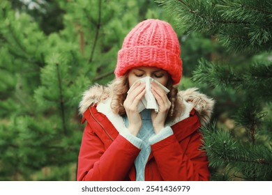 Sick exhausted woman sneezing blow nose using tissue, unhealthy suffering girl feels unwell outdoors in winter park - Powered by Shutterstock