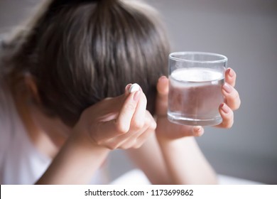 Sick frustrated woman feel unwell holding glass of water and pill doubting to take medicine, exhausted female suffer from migraine or headache ready to have antibiotic or painkiller to ease symptoms - Shutterstock ID 1173699862