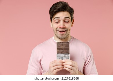 Sick Fun Unhealthy Ill Allergic Man Has Red Watery Eyes, Runny Stuffy Sore Nose Suffer From Allergy Trigger Symptoms Feel Bad Hold In Hand Chocolate Bar Isolated On Pastel Pink Color Background Studio