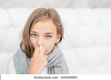 Sick girl with flu using nose spray at home. Empty space for text