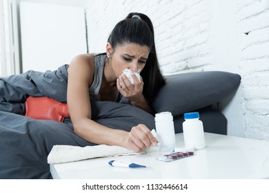 Sick Hispanic Woman In Bed Calling In Sick Day Off From Work Thermometer To Check Temperature For Fever And Vitamins Hot Water Bottle And Tissues In Cold And Flu Concept