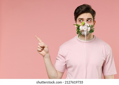 Sick ill allergic man has red watery eyes oxygen face mask with blooming flower plant difficulty breathing suffer from allergy trigger symptom hay fever isolated on pastel pink color background studio - Powered by Shutterstock