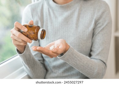 Sick ill asian young woman, girl hold tablet pill on hand pour capsule from medication bottle, painkiller medicine from stomach pain, head ache, pain for treatment, take drug or vitamin, health care. - Powered by Shutterstock