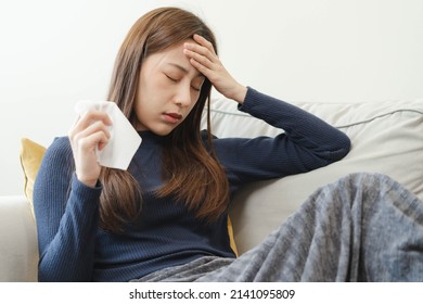 Sick, influenza asian young woman, girl headache have a fever, flu and check measure body temperature, feel illness sitting on sofa bed at home. Health care person on virus, covid-19. - Shutterstock ID 2141095809