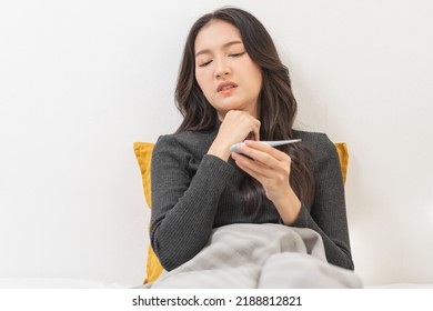 Sick, Influenza Asian Young Woman, Girl Have Sore Throat, Hand Using Thermometer Measure Body Temperature, Check A Fever, Flu And Feeling Illness Sitting On Bed At Home. Health Care People.