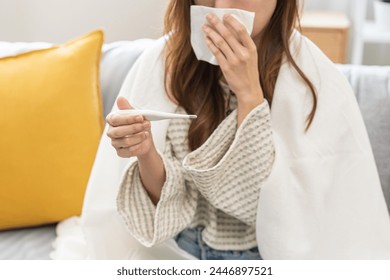 Sick, influenza asian young woman tired have a fever and sore cough hand holding thermometer for check measure body temperature, illness while rest at home. Health care with disease, pandemic virus. - Powered by Shutterstock