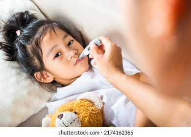 Sick kid. Mother parent checking temperature of her sick daughter with digital thermometer in mouth, child laying in bed taking measuring her temperature for fever and illness, healthcare - Powered by Shutterstock