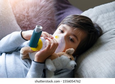 Sick Kid Tired From Chest Coughing Holding Inhaler Mask,Patient Child Boy Lying In Bed Using The Volumtic For Breathing Treatment,Tried Kid Having Asthma Allergy Using The Asthma Inhaler 