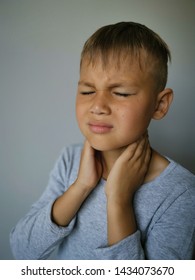 Sick Kid Touching His Painful Neck, Sore Throat And Flu, Throat Infection. Isolated On Gray Background.