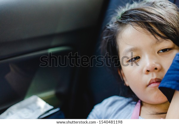Sick little asian girl make tired face\
and sleepy in the taxi car.She going to\
hospital.