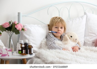 Sick Little Blond Toddler Boy, Lying In Bed With Fever, Hugging Little Fluffy Toy, Medicine Next To Him On The Night Stand