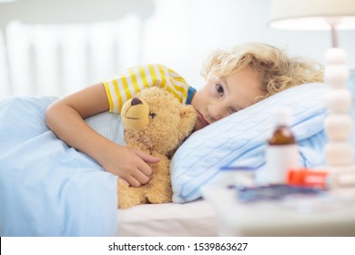 Sick little boy with asthma medicine. Ill child lying in bed. Unwell kid with chamber inhaler for cough treatment. Flu season. Bedroom or hospital room for young patient. Healthcare and medication. - Shutterstock ID 1539863627