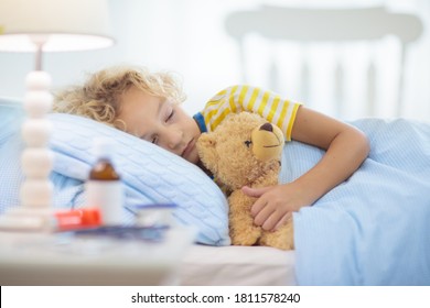 Sick little boy with asthma medicine. Ill child lying in bed. Unwell kid with chamber inhaler for cough treatment. Flu season. Bedroom or hospital room for young patient. Healthcare and medication. - Shutterstock ID 1811578240