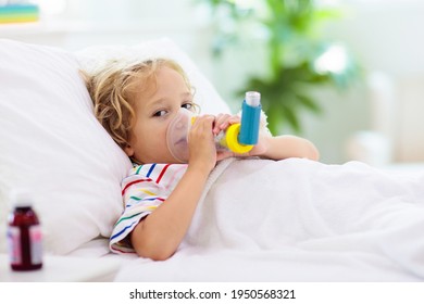 Sick Little Boy With Asthma Medicine. Ill Child Lying In Bed. Unwell Kid With Chamber Inhaler For Cough Treatment. Flu Season. Bedroom Or Hospital Room For Young Patient. Healthcare And Medication.