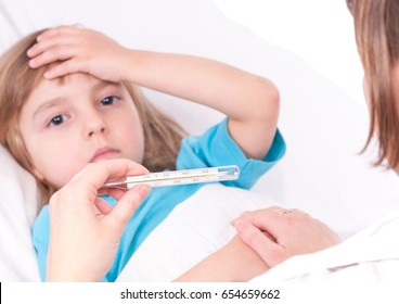 Sick little girl in bed. Mother or doctor with thermometer is sitting near the bed. Focus on thermometer.