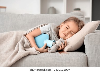 Sick little girl with hot water bottle and toy lying on sofa at home - Powered by Shutterstock