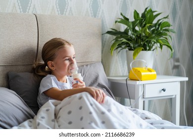 Sick Little Girl Making Inhalation With Nebulizer To Reduce Coughing, Lying In Bed At Home, Child Taking Medication While Breathing In Through Face Mask. Bronchitis And Asthma Treatments For Children