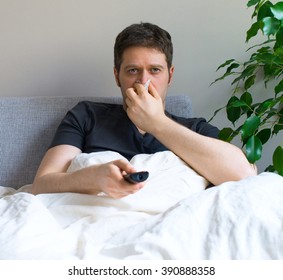 Sick Man Blowing His Nose While Watching TV At Home.