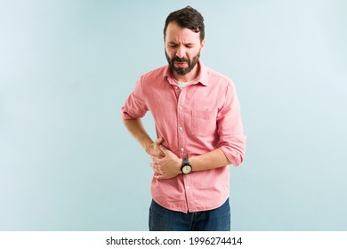 Sick man having pain due to gallstones. Latin young man with a gallbladder disease touching a side of his stomach - Shutterstock ID 1996274414