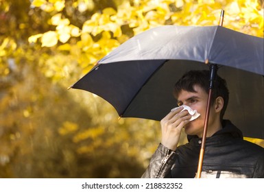 Sick Man Holding Umbrella  And  Blowing Nose At Autumn Day