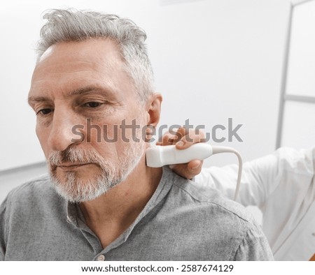 Sick man looking for causes of headache while getting ultrasound scan of neck vessels to find diagnosis. Vascular ultrasound, close-up