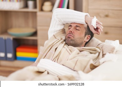 Sick Man Lying Down On Couch With High Fever