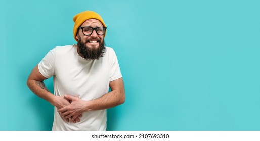 A sick man is in severe pain due to gallstones. A young man with a beard suffers from gallbladder disease. Copy space for your text. - Shutterstock ID 2107693310