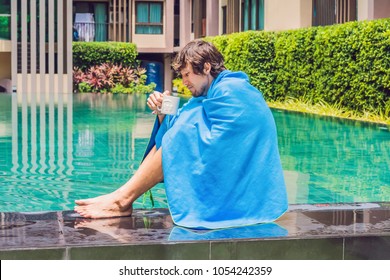 Sick Man Traveler. The Man Caught A Cold On Vacation, Sits Sad At The Pool Drinking Tea And Blows His Nose Into A Napkin