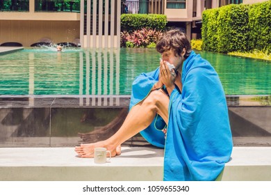 Sick Man Traveler. The Man Caught A Cold On Vacation, Sits Sad At The Pool Drinking Tea And Blows His Nose Into A Napkin