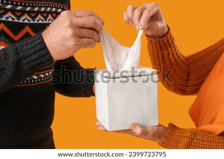 Sick mature couple taking tissue from box on yellow background, closeup