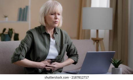 Sick Mature Woman With Laptop Bad Pain Hold Belly Stomach Suffer With Hurt Abdomen Ache At Home, Old Lady Feels Gastritis Pancreatitis Symptom Sit On Couch, Upset Senior With Indigestion Flatulence