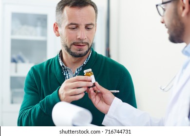 Sick patient taking pill-bottle with medication or vitamins from doctor hands - Shutterstock ID 716744731
