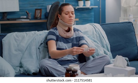 Sick Person With Cervical Foam For Vertebra Injury Looking At Tablet With Capsules And Pills. Injured Woman Wearing Medical Neck Collar To Cure Muscle Pain While Feeling Ill Because Of Flu