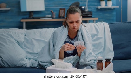 Sick Person Looking At Capsule Tablets And Bottle Of Pills For Disease Treatment. Woman In Blanket Reading Labels Of Medicaments Against Cold And Flu. Adult With Prescription Medicine