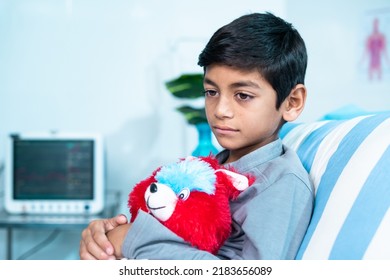 Sick sad thoughtful child with teddy bear sitting on admitted hospital bed - concept of disease, rehabilitation and medical treatment - Powered by Shutterstock